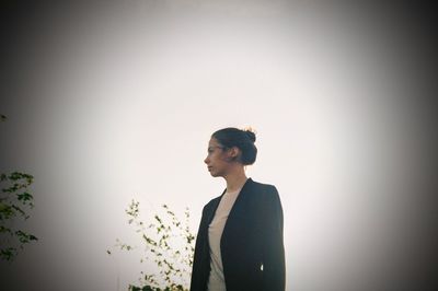 Young woman looking away against wall