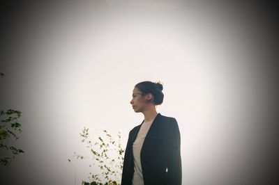 Young woman looking away against sky