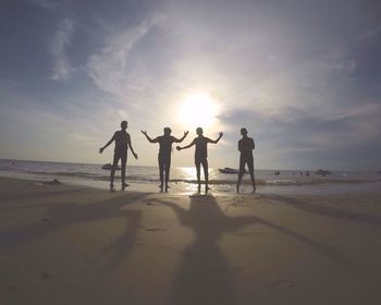 Full length of silhouette friends at beach against sky during sunset