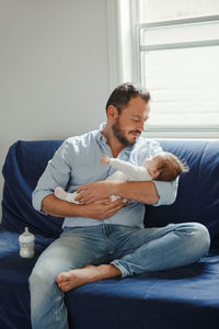 Father sitting with baby girl on sofa