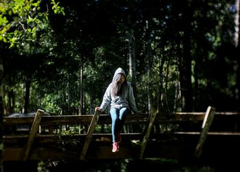 Young woman sitting on footbridge in park