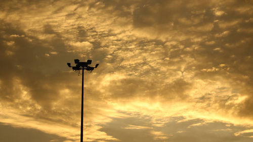 Low angle view of weather vane against cloudy sky