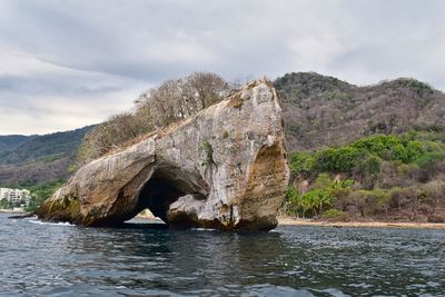 Scenic view of rock formation in water against sky