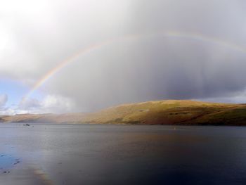 Scenic view of rainbow over sea against sky