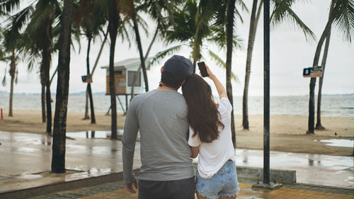 Rear view of couple standing by palm trees