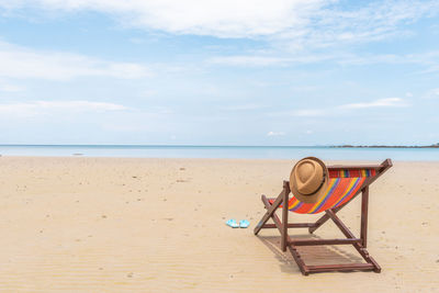 Deck chairs on beach against sky