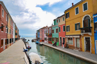 Canal amidst buildings in city against sky