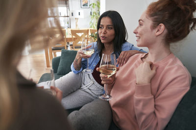 Smiling friends talking while drinking wine