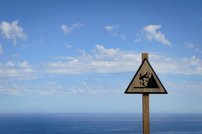 Sign board against sea and sky