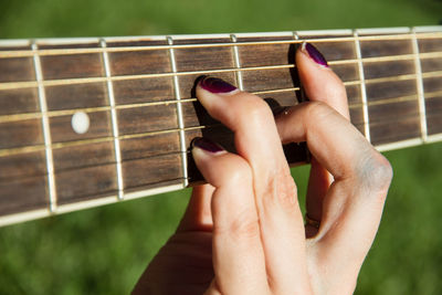 Cropped hand of woman playing guitar at public park