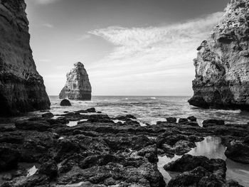 Rock formation on beach against sky