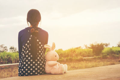 Rear view of girl sitting with toy