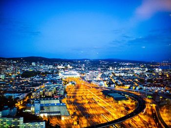 High angle view of illuminated cityscape against blue sky