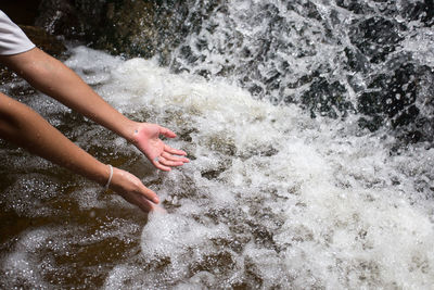 Close-up of woman reaching into water