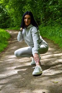 Full length of woman sitting on footpath