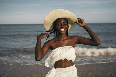 Portrait of smiling young woman standing on beach