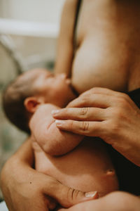 Midsection of woman breastfeeding newborn son at home