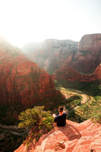 Rear view of man sitting on mountain