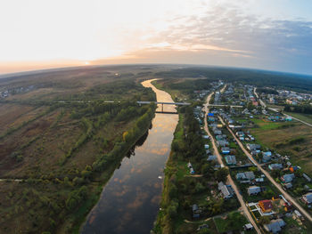 Aerial view of town by river against sky during sunset