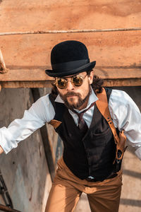 Midsection of man holding hat against wall