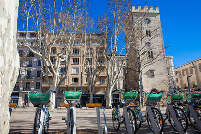 Bicycles parked on street by building against blue sky