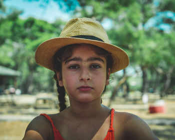 Close-up portrait of cute girl wearing hat while sitting outdoors