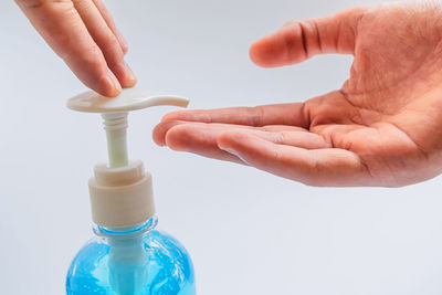 Close-up of hand holding bottle against white background