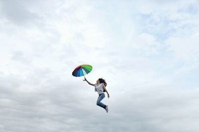 Low angle view of boy jumping against sky