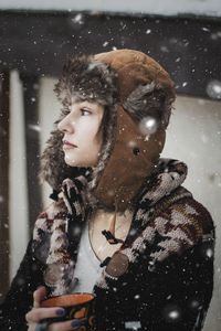 Woman looking away outdoors during snowfall