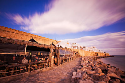 View cafe by sea against cloudy sky