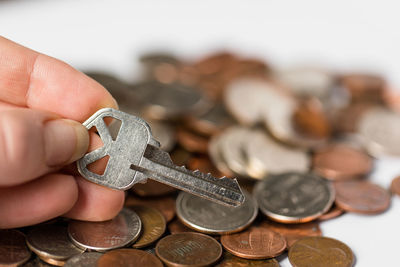 Close-up of hand holding key, coins in background