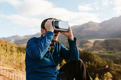 Rear view of man using mobile phone against mountains