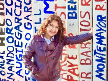 Portrait of smiling woman standing against text on wall