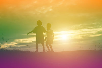 Silhouette men standing on land against sky during sunset