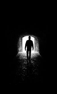 Rear view of silhouette man walking in tunnel