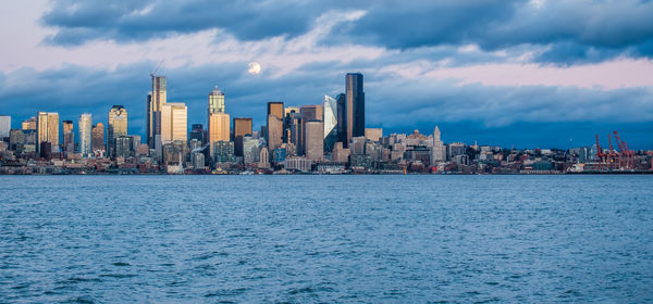 A full moon shines above the seattle skyline.