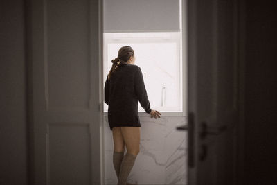 Rear view of woman standing against door