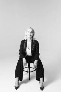 Portrait of woman sitting on chair against white background