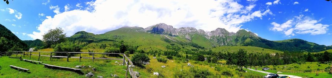 Panoramic view of green landscape and mountains against sky