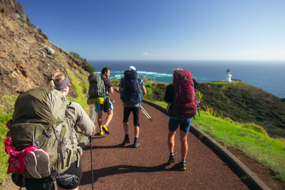 Rear view of people walking by sea against clear sky