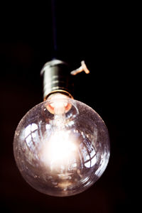 Close-up of illuminated light bulb against black background