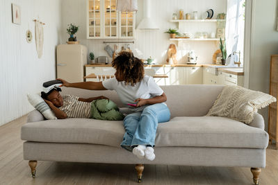 Young woman using digital tablet while sitting on sofa at home