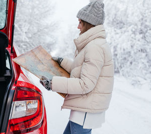 Midsection of woman holding umbrella standing in snow