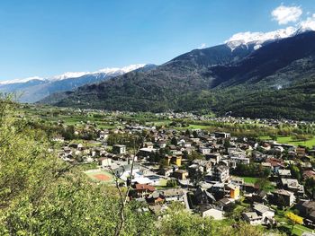 Aerial view of townscape by mountains against sky