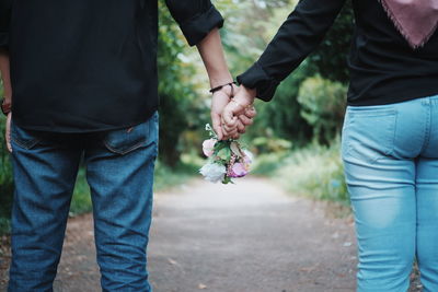 Rear view of couple holding hands at park