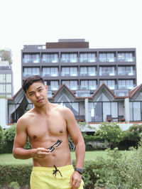 Shirtless man standing against building