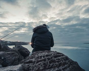 Rear view of man looking at sea against sky