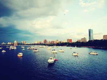 Boats in harbor against cloudy sky