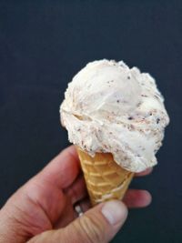 Hand holding ice cream cone against black background