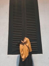 Woman wearing hijab standing by window outdoors